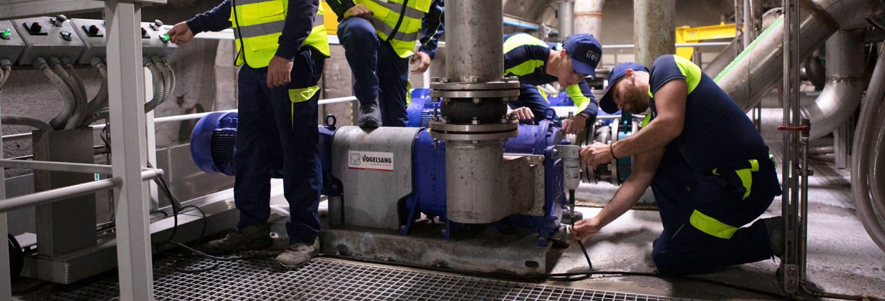 Quattro dipnedenti Iren con la divisa tecnica lavorano in un depuratori accanto ad un macchinario