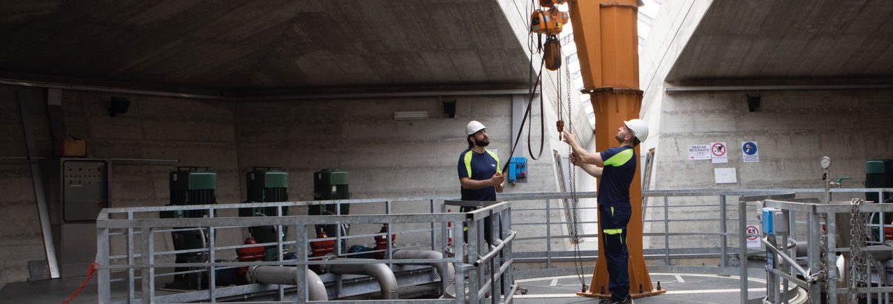 Due dipendenti Iren all'interno di un impianto Iren lavorano con i caschetti di protezione