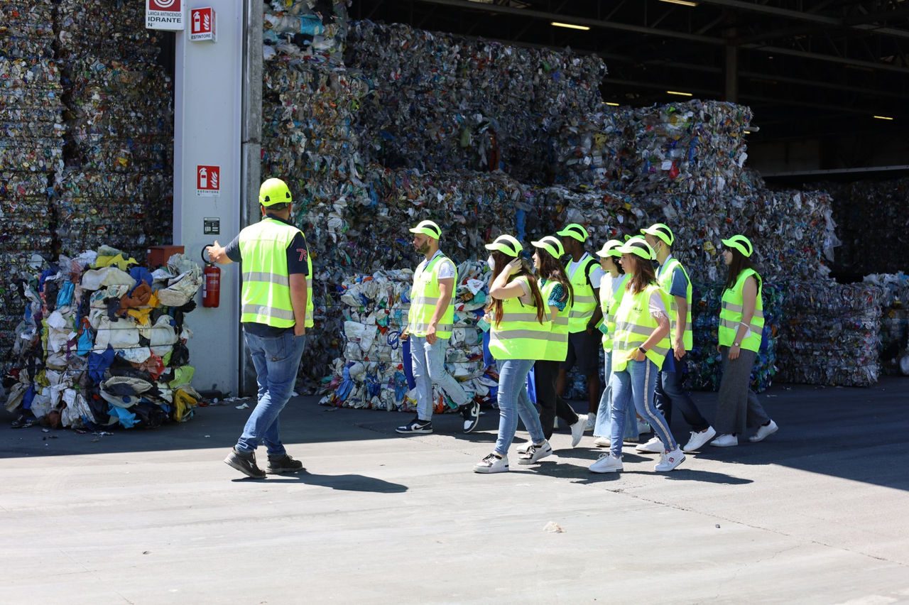 Gruppo di visitatori con il gilet di protezione cammina in una discarica