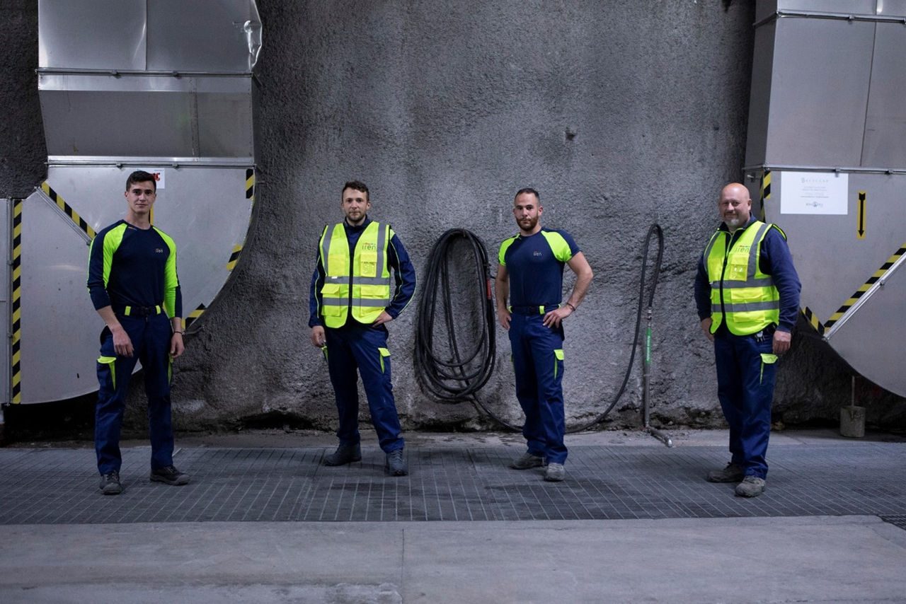 Quattro dipendenti Iren con l'abbigliamento tecnico osservano in camera all'interno di un impianto di depurazione